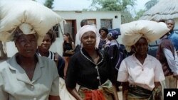 FILE: Unidentified rural women in Seke, Zimbabwe, 120 kilometres east of Harare, carry bags of donated maize from a food distribution point on Monday, Oct. 7, 2002. 