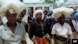 FILE: Unidentified rural women in Seke, Zimbabwe, 120 kilometres east of Harare, carry bags of donated maize from a food distribution point on Monday, Oct. 7, 2002. Seke is just one of many food distribution centers throughout Zimbabwe, which have been se