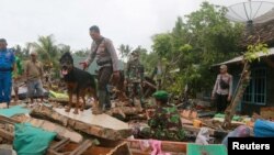 Regu penyelamat menggunakan anjing pelacak untuk melakukan pencarian korban, di antara puing-puing bangunan yang berserakan akibat hantaman tsunami Selat Sunda di Rajabasa, Lampung Selatan, 25 Desember 2018. 