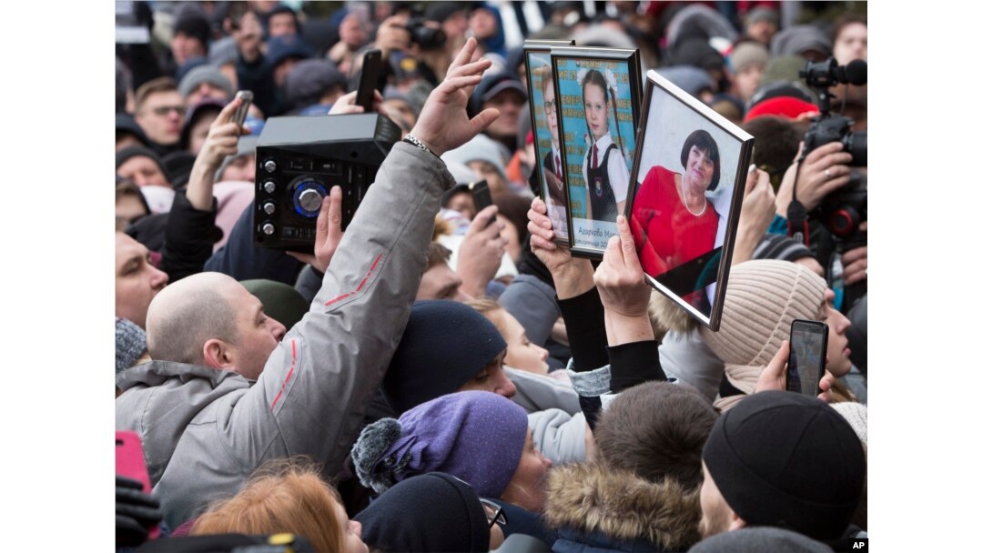 People hold portraits of relatives as they gather to remember the victims of a fire in a multi-story shopping center in the Siberian city of Kemerovo, about 3,000 kilometers (1,900 miles) east of Moscow, Russia, March 27, 2018.