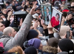 People hold portraits of relatives as they gather to remember the victims of a fire in a multi-story shopping center in the Siberian city of Kemerovo, about 3,000 kilometers (1,900 miles) east of Moscow, Russia, March 27, 2018.