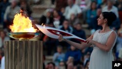Aktris Ino Menegaki, berperan sebagai pendeta, menyalakan obor dengan api Olimpiade di dalam upacara serah terima di Stadion Panathinaiko (5/10). 
