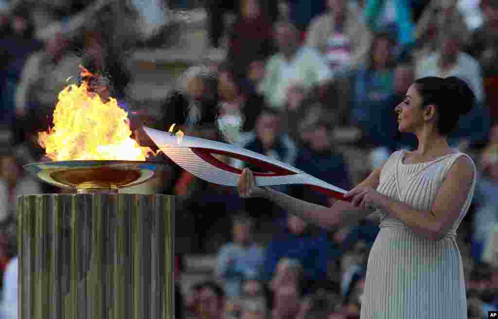 Actress Ino Menegaki, playing the role of high priestess, lights the torch with the Olympic Flame during a handover ceremony in Athens' Panathinaiko Stadium, Greece. After a seven-day run through Greece, the flame will cover 40,000 miles on Russian soil.