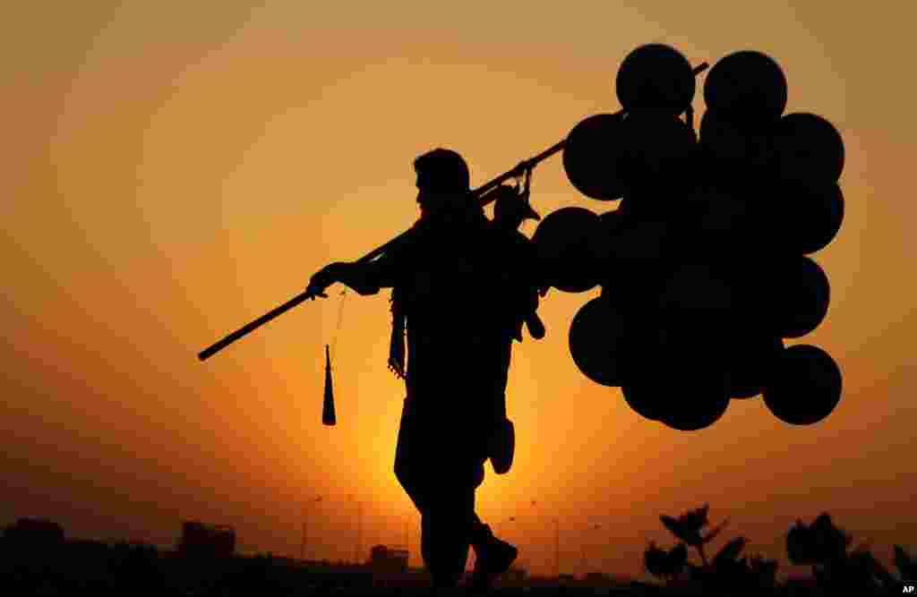 A Pakistani vendor heads home carrying his unsold balloons, in Lahore, during sunset.