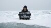Aktivis lingkungan, Mya-Rose Craig, memegang spanduk bertuliskan "youth strike for climate" atau (pemuda mogok demi iklim" selagi duduk di atas es di tengah laut Arktik, September 2020 (Dok: REUTERS/Natalie Thomas)