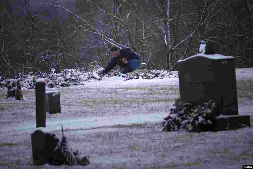 A man touches the snow covered grave of six-year-old Ana Grace Marquez-Greene, one of 20 schoolchildren killed in the December 14 shootings at Sandy Hook Elementary School, at the Newtown Village Cemetery, Connecticut, December 25, 2012. 