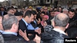 Presiden Suriah Bashar al-Assad (tengah) mengunjungi para pendukungnya di distrik Baba Amr, kota Homs (27/3). 