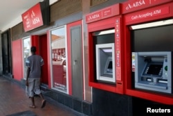 FILE - A man walks past a branch of South Africa's biggest retail bank, Absa, in Cape Town, Dec. 6, 2012
