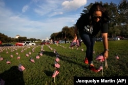 FILE - Patrice Sullivan, yang pacarnya, seorang Marinir, meninggal karena bunuh diri, membantu menyingkirkan 5.000 bendera kecil Amerika, dalam aksi yang diprakarsai oleh Veteran Irak dan Afganistan Amerika (IAVA), di Washington, D.C. (Jacquelyn Martin/AP)