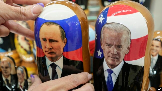 A customer shows to photographer a traditional Russian wooden dolls called Matreska of Russian President Vladimir Putin, center, and U.S. President Joe Biden, center right, at a souvenirs store in Moscow, Russia, Dec. 6, 2021.