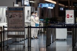 Staff members stand at the departure gate of Tokyo's Haneda international airport on Nov. 29, 2021, as Japan announced plans to bar all new foreign travelers over the omicron variant of COVID-19.