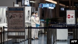 Staff members stand at the departure gate of Tokyo's Haneda international airport on Nov. 29, 2021, as Japan announced plans to bar all new foreign travelers over the omicron variant of COVID-19. 