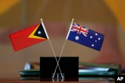 Bendera Timor Leste, kiri, dan Australia dikibarkan dalam upacara di markas besar PBB, 6 Maret 2018. (Foto: AP)