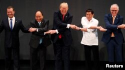  U.S. President Donald Trump smiles with other leaders, including Russia's Prime Minister Dmitry Medvedev, Vietnam's Prime Minister Nguyen Xuan Phuc, President of the Philippines Rodrigo Duterte and Australia's Prime Minister Malcolm Turnbull, as they cross their arms for the traditional "ASEAN handshake" in the opening ceremony of the ASEAN Summit in Manila, Philippines, Nov. 13, 2017. 