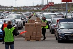 Using part of the Pittsburgh International Airport parking lot, that has been left vacant by the COVID-19 pandemic, volunteers from the Greater Pittsburgh Community Food Bank, load boxes of food into cars during a drive-up food distribution.