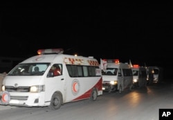 In this photo released by the Syrian official news agency SANA, ambulances of the Syrian Arab Red Crescent line up during a mission to evacuate sick and wounded people from the eastern Ghouta, near Damascus, Syria, Dec. 28, 2017.