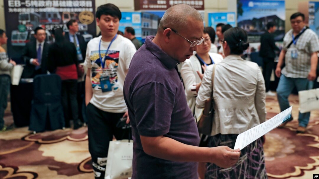 A Chinese man reviews a leaflet at the exhibitor booths in a Invest in America Summit, a day after an event promoting EB-5 investment in a Kushner Companies development in Beijing, May 7, 2017. The sister of President Trump's son-in-law Jared Kushner has been in China courting individual investors with a much-criticized federal visa program that provides a path toward obtaining U.S. green cards. 