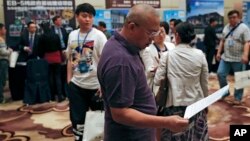 A Chinese man reviews a leaflet at the exhibitor booths in a Invest in America Summit, a day after an event promoting EB-5 investment in a Kushner Companies development in Beijing, May 7, 2017. The sister of President Trump's son-in-law Jared Kushner has been in China courting individual investors with a much-criticized federal visa program that provides a path toward obtaining U.S. green cards. 