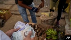 Foto de archivo. Un vendedor cuenta bolívares y billetes de dólares estadounidenses en un mercado público en el barrio Quinta Crespo en Caracas, Venezuela. (Foto AP/Matías Delacroix)