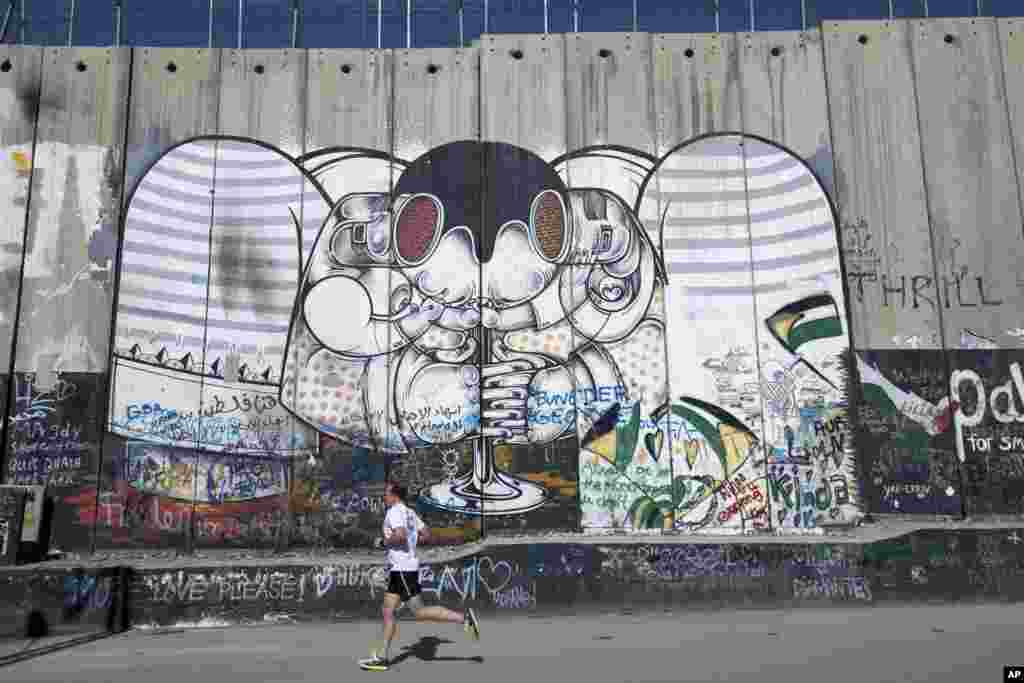 A runner taking part in the Palestine Marathon passes by the Israeli separation barrier in the West Bank city of Bethlehem.