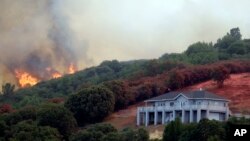 Las llamas de un incendio amenazan un casa en Lakeport, California, el lunes, 30 de julio de 2018.