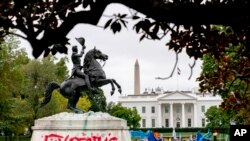 The words &quot;Expect Us&quot; are spray-painted on the base of the Andrew Jackson statue in Lafayette Park as Indigenous and environmental activists protest in front of the White House in Washington.