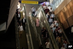 On what some have called "Freedom Day" marking the end of coronavirus restrictions in England, commuters take escalators and stairs after disembarking from a train at London Bridge train station in London, July 19, 2021.