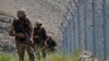 FILE - Pakistani troops patrol along Pakistan-Afghanistan border fence in the Khyber district of the Khyber Pakhtunkhwa province, Aug. 3, 2021. 