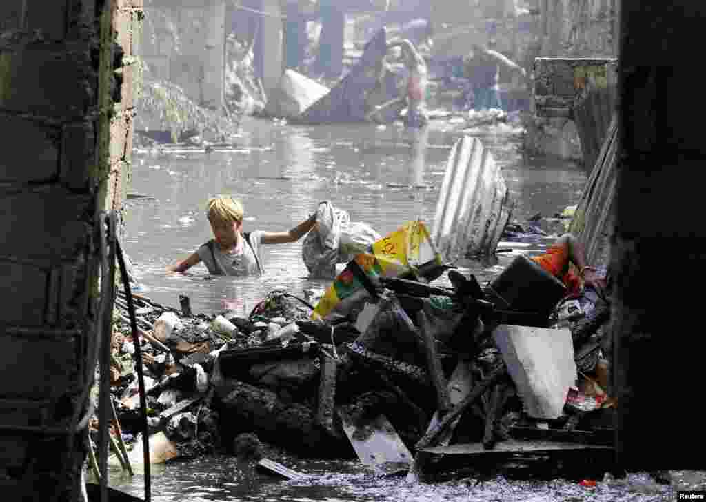 Seorang anak laki-laki mengumpulkan barang-barang yang masih bisa dipakai di sebuah sungai kecil setelah kebakaran melanda permukiman kumuh di Caloocan City, pinggiran ibukota Manila, Filipina.