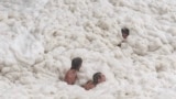 Young men play in sea foam created by record-breaking waves as the outer fringe of Tropical Cyclone Alfred started whipping eastern Australia, in Coolangatta, March 6, 2025. 