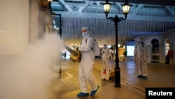 Para relawan menggunakan baju hazmat menyemprotkan disinfektan di pusat perbelanjaan di Wuhan, Provinsi Hubei, 31 Maret 2020. Hubei menjadi pusat wabah virus corona di China. (Foto: Reuters). 