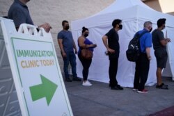 FILE- People wait in line for COVID-19 vaccinations at an event at La Bonita market, a Hispanic grocery store, in Las Vegas, July 7, 2021.