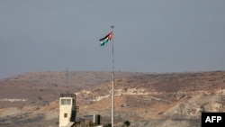 FILE - A picture taken Oct. 18, 2019, from the Israeli side of the border at the Jordan Valley site of Naharayim, shows a Jordanian flag flying over a military outpost. 