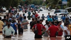 Residents wade through a flooded road in the aftermath of Hurricane Eta in Planeta, Honduras, Nov. 5, 2020. 