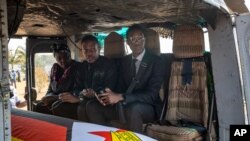 FILE: Former president Robert Mugabe's two sons Chatunga Mugabe, center, and Robert Mugabe Junior, right, accompany his casket in an air force helicopter for transport to a stadium where it will lie in state, in the capital Harare, Zimbabwe, Sept. 13, 2019. 