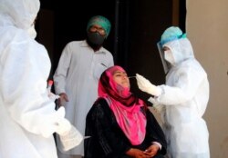 Health workers take a nasal swab sample during a door-to-door testing and screening operation for the new coronavirus, in Hyderabad, Pakistan, June 17, 2020.
