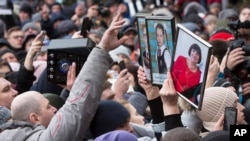 People hold portraits of relatives as they gather to remember the victims of a fire in a multi-story shopping center in the Siberian city of Kemerovo, about 3,000 kilometers (1,900 miles) east of Moscow, Russia, March 27, 2018.