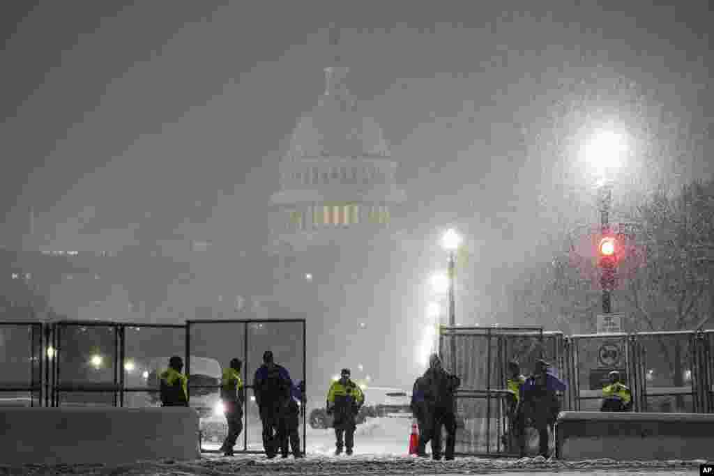 Agentes encargados de hacer cumplir la ley hacen guardia en el Capitolio mientras cae nieve antes de una sesión conjunta del Congreso para certificar los votos del Colegio Electoral en las elecciones presidenciales, en Washington.