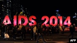 People gather next to a sign reading AIDS 2014 in Melbourne on July 18, 2014 after news that downed Malaysia Airlines flight MH17 was carrying many participants headed to the 20th International AIDS Conference planned this weekend in the Australian city. 