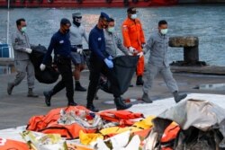 Personel DVI dan TNI Angkatan Laut membawa tas berisi bagian tubuh penumpang Sriwijaya Air penerbangan SJ-182 yang jatuh ke laut, di pelabuhan Tanjung Priok, Jakarta, 13 Januari 2021. (Foto: Reuters)