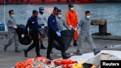 Indonesian DVI and navy personnel carry bags with body parts of the passengers of Sriwijaya Air flight SJ-182, which crashed to the sea, at Tanjung Priok port in Jakarta, Indonesia, Jan. 13, 2021.