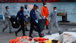 Personel DVI dan angkatan laut membawa tas berisi bagian tubuh penumpang Sriwijaya Air penerbangan SJ-182 yang jatuh ke laut, di pelabuhan Tanjung Priok, Jakarta, 13 Januari 2021. (Foto: Reuters)