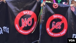 Two protesters against the controversial LANGO stand opposite the Cambodian Senate building as the bill is debated early Friday. (Robert Carmichael for VOA News)