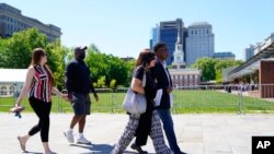 From left, Brooke Vaughn and husband former NFL player Clarence Vaughn III, Amy Lewis and husband former NFL player Ken Jenkins carry petitions demanding equal treatment in the NFL concussion settlement to the Philadelphia courthouse May 14, 2021.