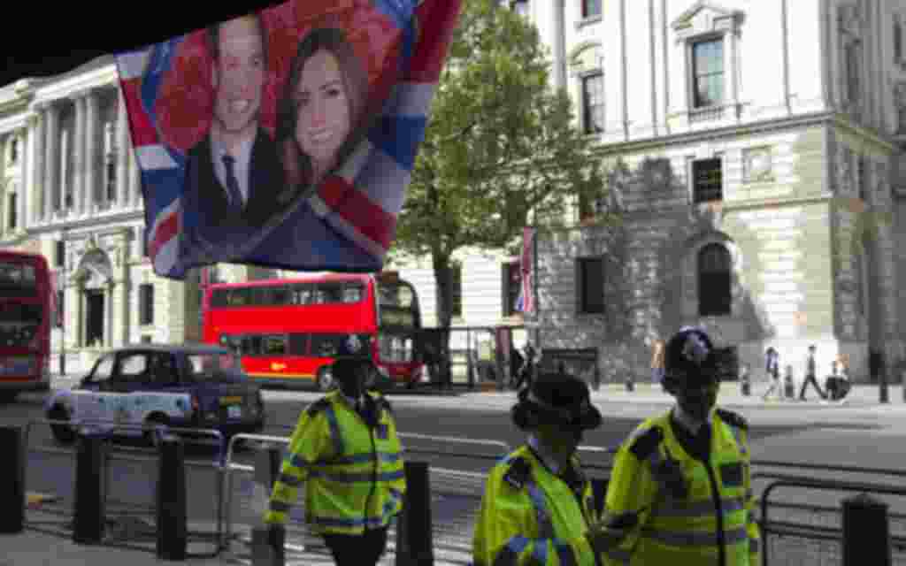 Police officers walk past a flag hanging outside a coffee shop, depicting Britain's Prince William and Kate Middleton, on Whitehall, in central London April 27, 2011. Prince William will marry Kate Middleton at Westminster Abbey on April 29th. REUTER