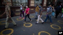 Yellow circles on a pavement serve as visual cues to help shoppers adhere to social distancing when lines form, as a precaution against the spread of the new coronavirus, near a popular market in Caracas, Venezuela, May 23, 2020. 