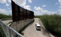 FILE - A U.S. Customs and Border Patrol vehicle is seen driving along a border fence, in Hidalgo, Texas, June 27, 2018.