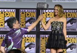 Director Taika Waititi hands the Thor hammer to Natalie Portman during the "Thor Love And Thunder" portion of the Marvel Studios panel on day three of Comic-Con International on July 20, 2019, in San Diego.