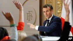 Members of the media raise their hands as French President Emmanuel Macron answers questions during a media conference at the Elysee Palace, April 25, 2019, in Paris.