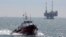 FILE - A service boat carries workers back to shore from a platform off Seal Beach, California, May 16, 2015. 